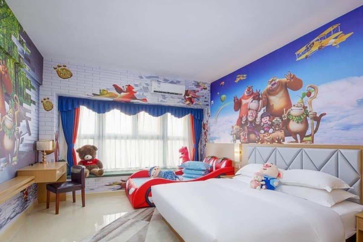 A child's bedroom with a large mural, a bed, a desk, and a window with curtains.