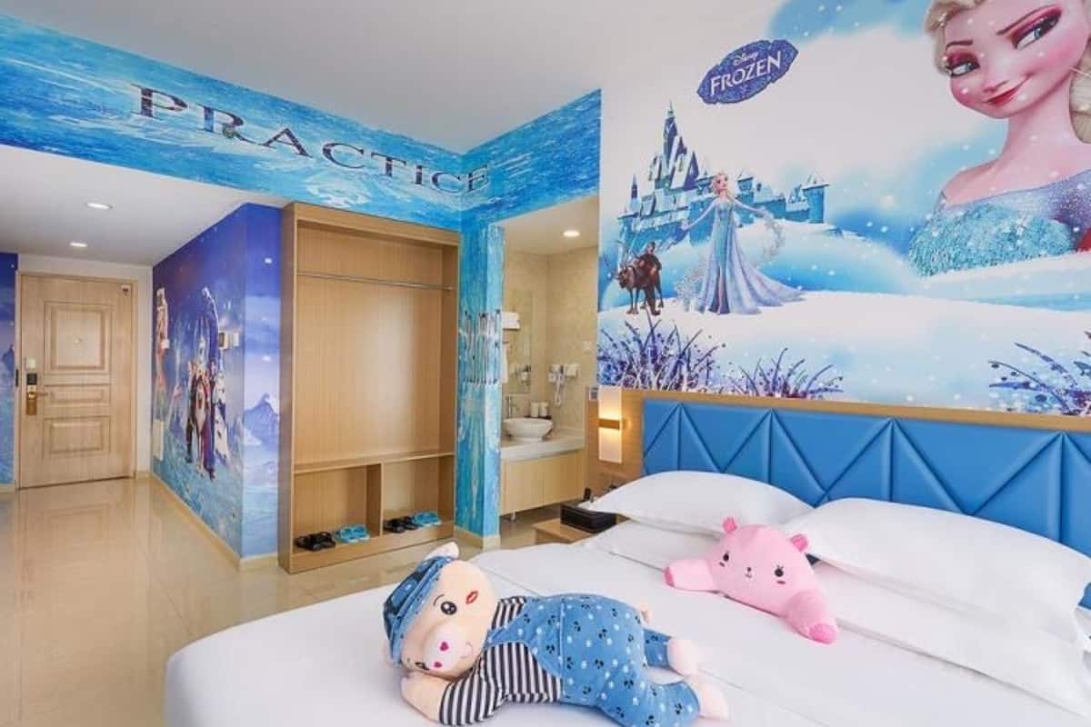 A children's room with a mural of Frozen, a wardrobe, a bed with toys, and a 'PRACTICE' sign on the wall.