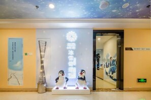 A reception area with a modern design, featuring a decorative wall with a celestial theme, a reception desk, and two penguin statues.