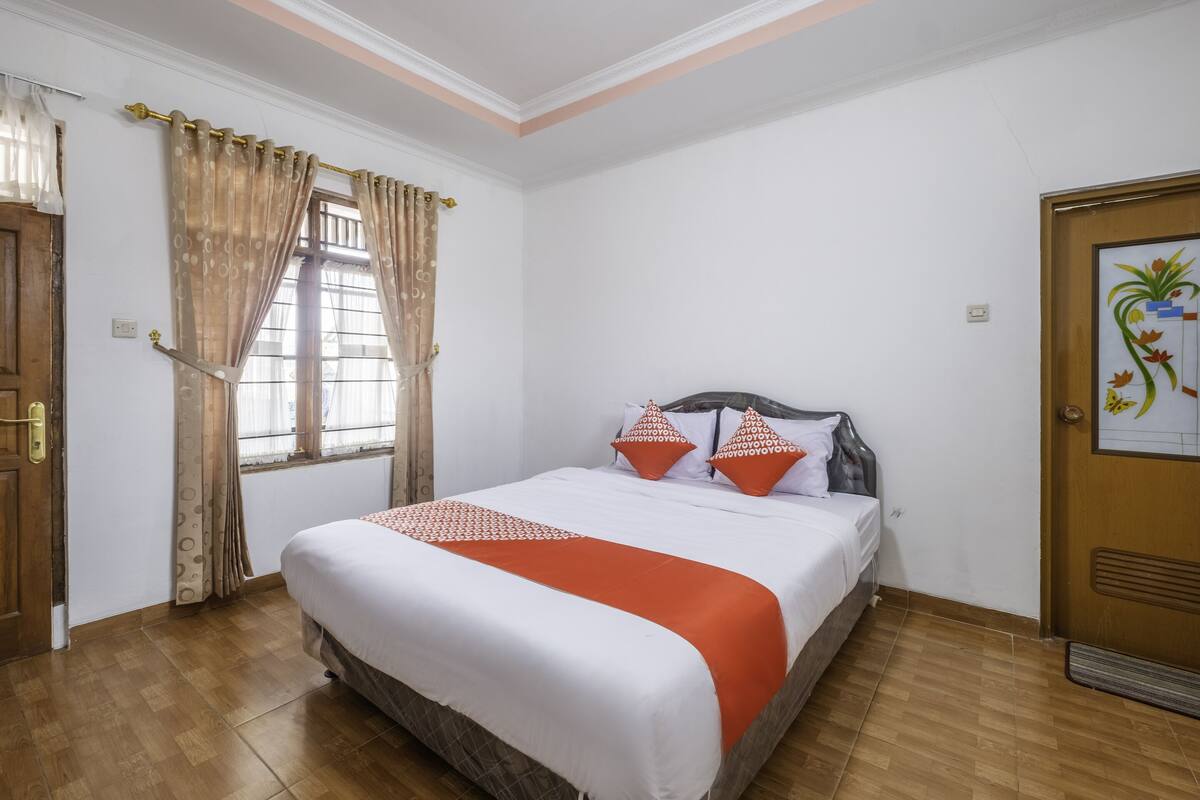 Ein ordentlich eingerichtetes Schlafzimmer mit Bett, Vorhängen und einer Tür.