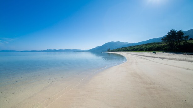 A beach with a clear sky and distant mountains. - Regina Ishigaki Kabira Sky (Ishigaki)