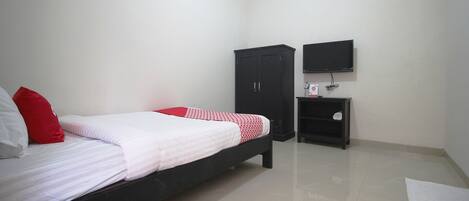 A bedroom with a bed, a wardrobe, a TV, and a small shelf.