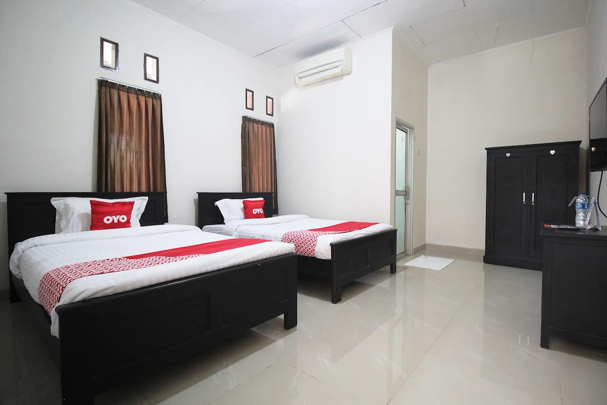 Habitación de hotel con dos camas, un armario y un equipo de aire acondicionado.