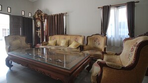 A traditional living room with a glass-top coffee table, two sofas, and matching armchairs. - Hotel O Wisma Ray Syariah (Bandar Lampung)
