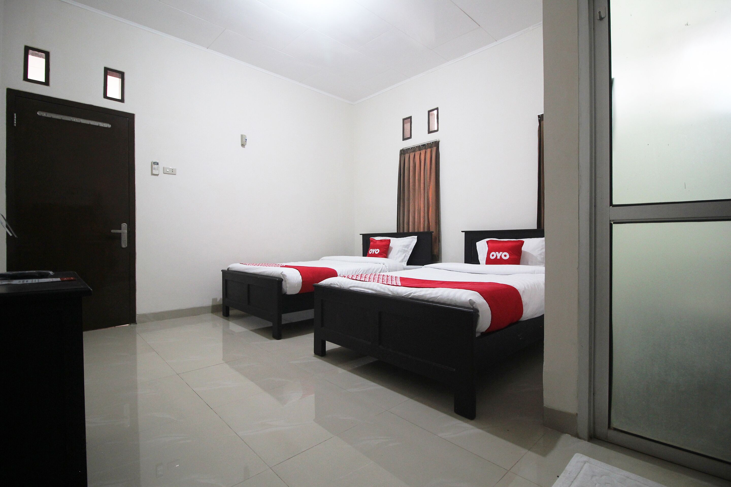 A hotel room with two beds, a desk, and a door.