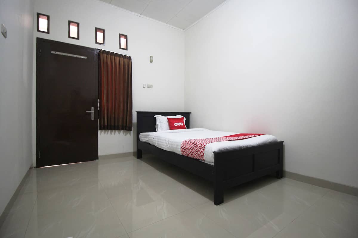 Un dormitorio con cama, puerta y ventana con cortinas.