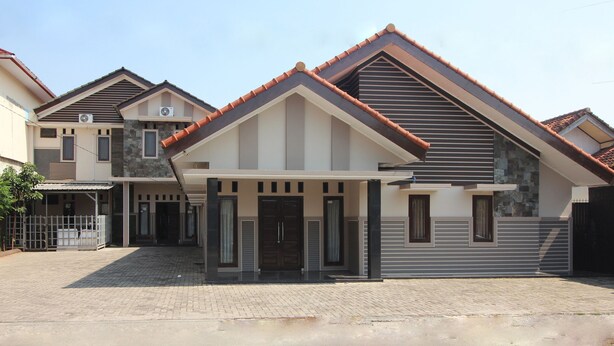 A modern two-story house with a tiled roof, a covered entrance, and a paved driveway. - Hotel O Wisma Ray Syariah (Bandar Lampung)