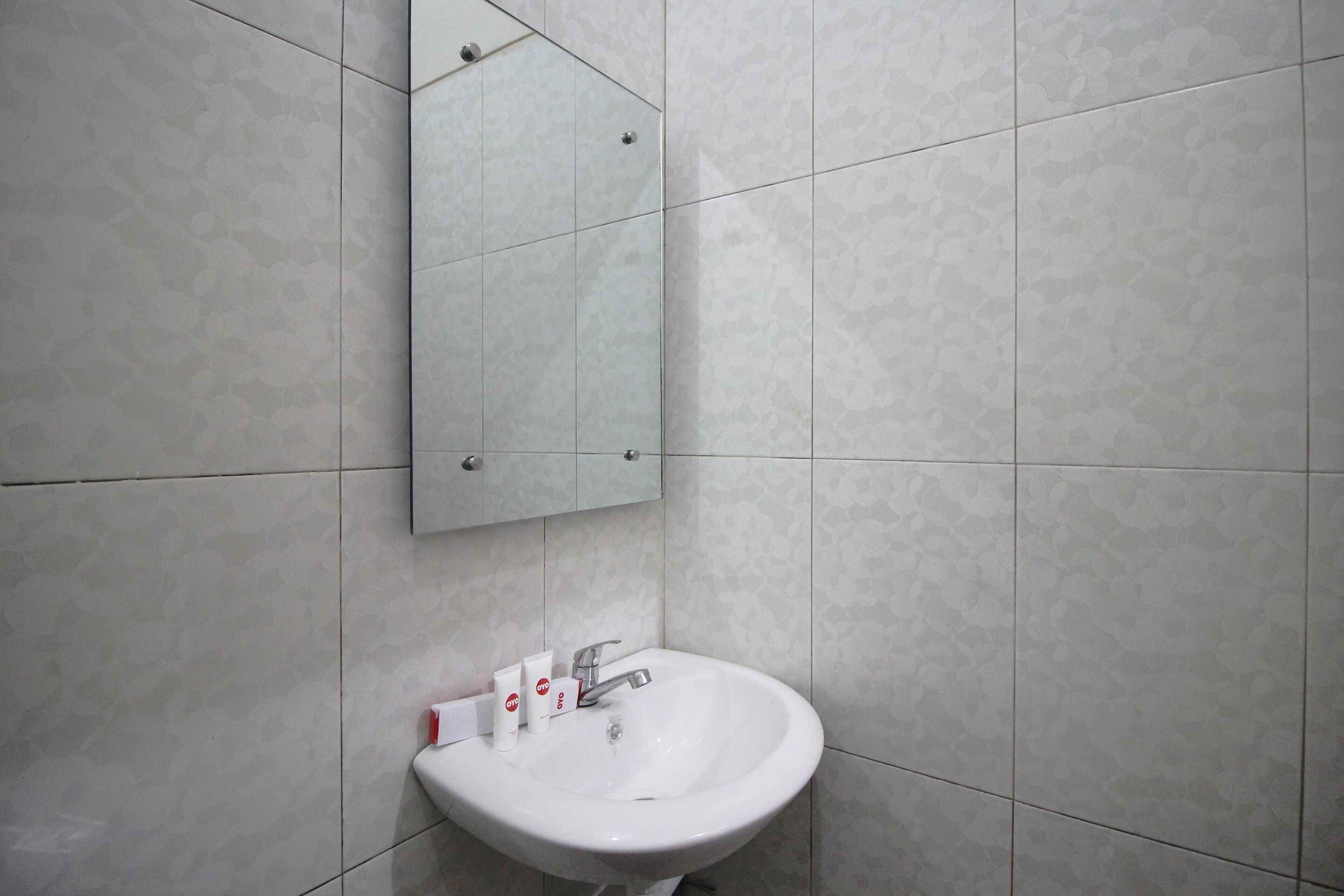 Une salle de bain avec un lavabo blanc, un miroir et des murs carrelés.