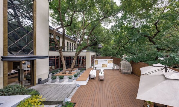 A courtyard with a wooden deck, outdoor seating, and a building with large windows. - Hefu Boutique Inn (Hangzhou)