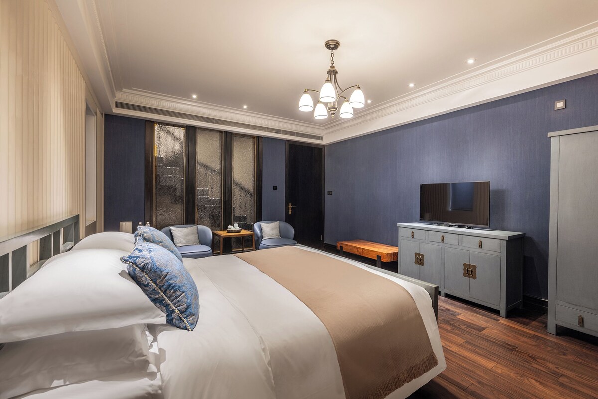 A bedroom with a large bed, a television on a cabinet, and a wardrobe.