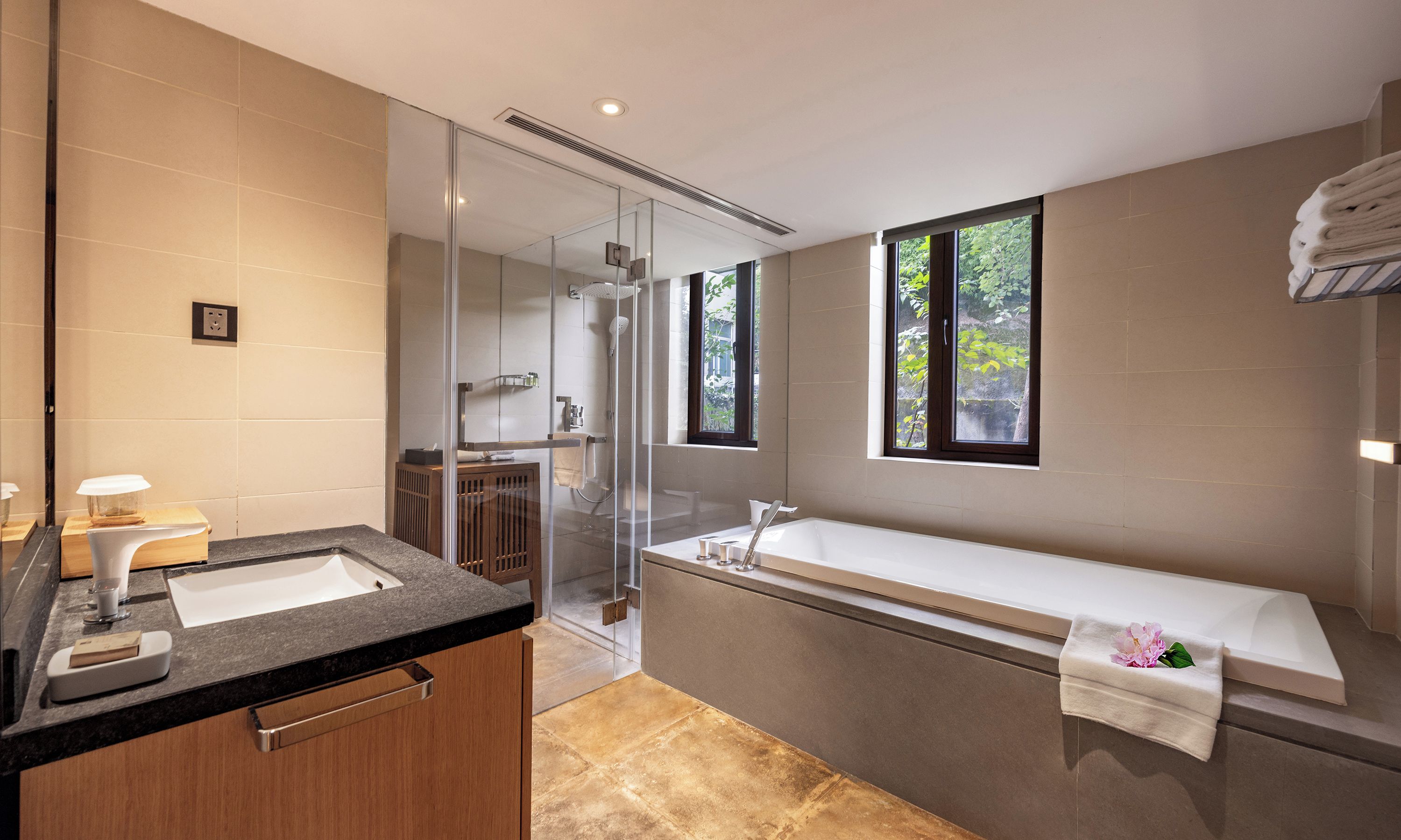 A modern bathroom with a glass-enclosed shower, a large bathtub, and a vanity with a mirror.