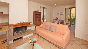 A living room with a sofa, a coffee table with a vase of flowers, a fireplace, and a dining area with a table and chairs. - Stella: with huge lake view balcony (Tignale)