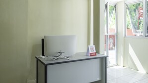 Une pièce propre et moderne, avec un bureau blanc, un ordinateur portable et un panneau indiquant l’endroit où s’enregistrer.