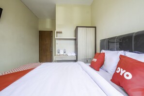 A hotel room with a bed, a wardrobe, a small table with toiletries, and a door. - OYO 2132 Pondok Avicenna (West Cirebon)