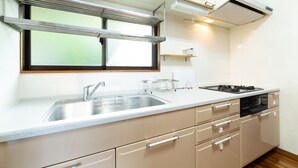 Una cocina moderna con un lavamanos de acero inoxidable, una estufa empotrada y armarios color beige.