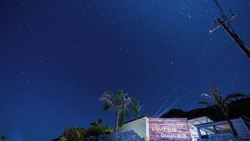 A starry night sky over a building with a sign in Japanese.