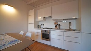 Een moderne keuken met witte kasten, een ingebouwde oven, een kookplaat en een roestvrijstalen spoelbak.