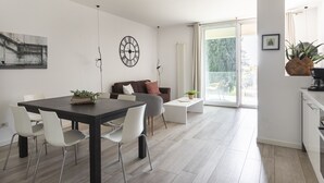 En modern inredning med ett matområde, en soffa, en kaffemaskin och utsikt genom en glasdörr.