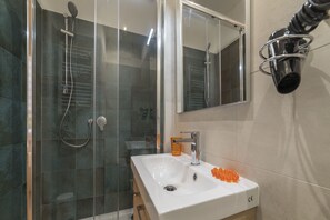 A bathroom with a glass-enclosed shower, a white sink, and a mirror. - Roman Station House (Rome)