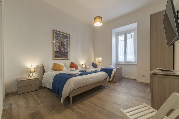 A bedroom with two beds, a desk, and a window. - Roman Station House (Rome)