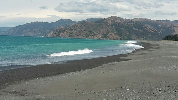 A beach with a clear view of the ocean and mountains in the background.