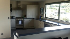 A kitchen with a stove, oven, and a window with a view of buildings.