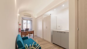 A compact living space with a kitchenette, a dining area with a blue chair, and a small table. - Roma Station House (Rome)