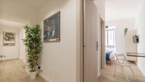 A modern, well-lit room with a large potted plant, a framed artwork, and a wooden floor. - Roma Station House (Rome)