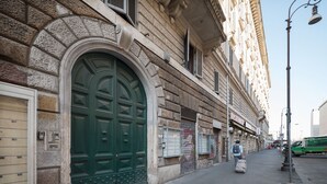A stone building with a large green door, a small window, and a street lamp. - Roma Station House (Rome)