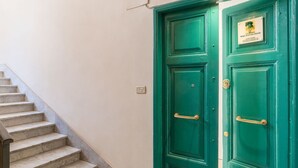 A green door with a plaque, a marble staircase, and a light switch on the wall. - Roma Station House (Rome)
