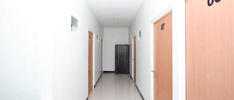 Un pasillo con puertas numeradas 06 y 07, que conduce a una puerta oscura al final.