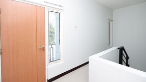 A room with a wooden door, a window, and a white wall. - Hotel O Palebon Residence (Semarang)
