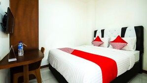 Una habitación de hotel con una cama, un escritorio de madera y una silla.