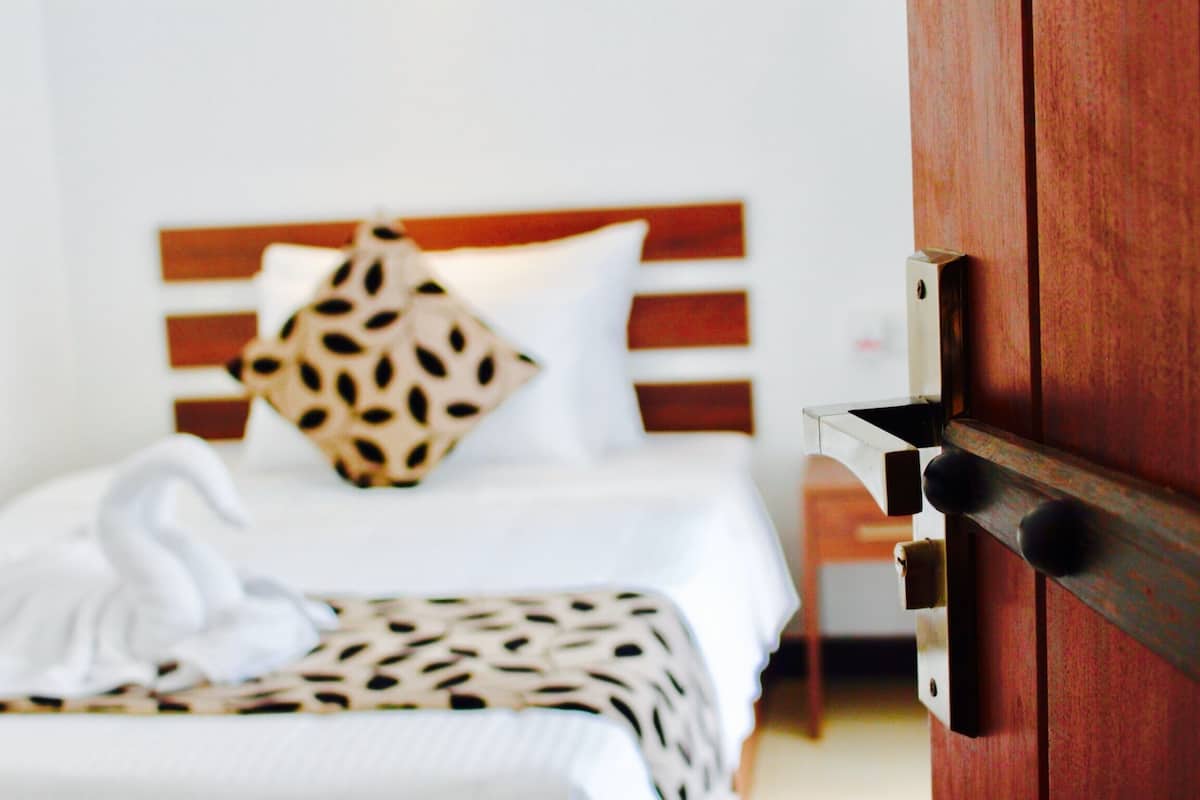 A hotel room with a bed featuring a patterned bedspread, a swan decoration, and a wooden headboard.