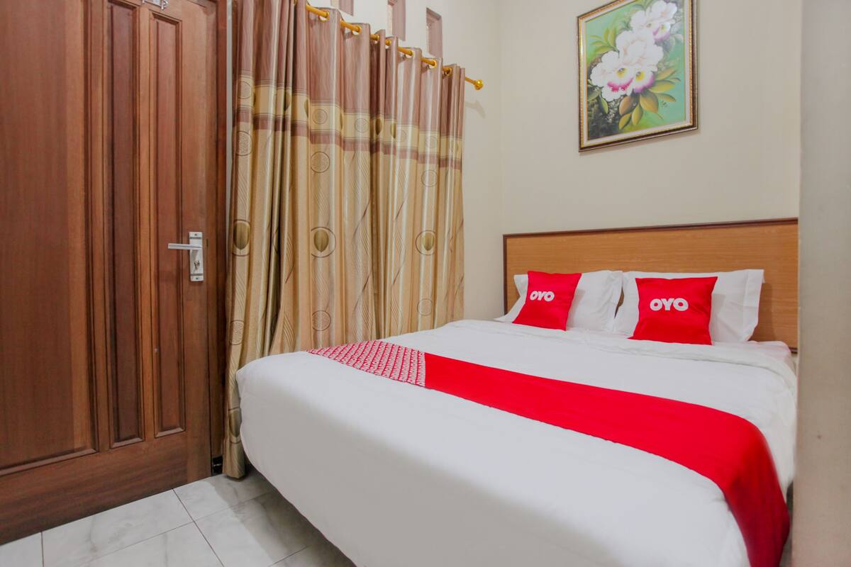 Una habitación de hotel con una cama, un armario de madera y un cuadro en la pared.