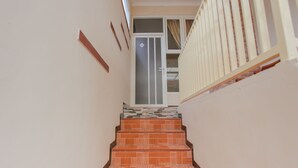 A staircase with red and white tiles leading to a door with a glass panel. - OYO 1692 Villa Akbar 3 (Batu)