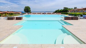 A swimming pool with a clear view of the sea in the background, surrounded by lounge chairs and umbrellas. - Fedra: with lake view balcony naer to the lake (Manerba del Garda)