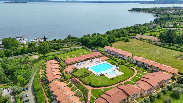 A large hotel with a central swimming pool, surrounded by lush greenery and a view of a lake. - Fedra: with lake view balcony naer to the lake (Manerba del Garda)