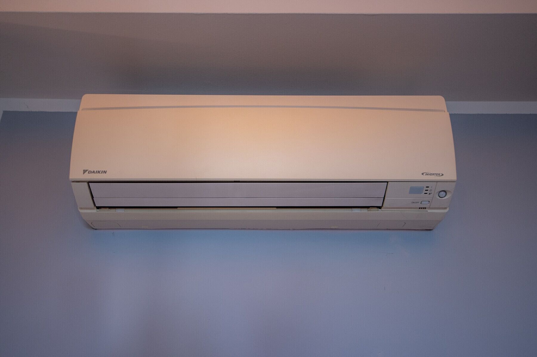 A Daikin inverter air conditioner unit on a blue floor.