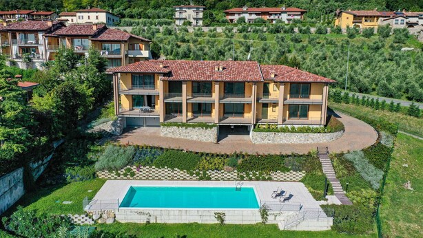 A multi-story building with balconies, a swimming pool, and a landscaped garden.