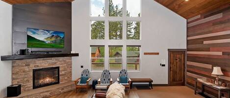 Un salón amplio con chimenea, ventanas grandes y un techo alto.