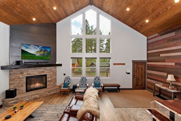Un salón amplio con chimenea, ventanas grandes y un techo alto.