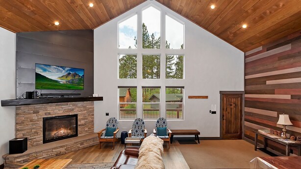 Un salón amplio con chimenea, ventanas grandes y techo alto.