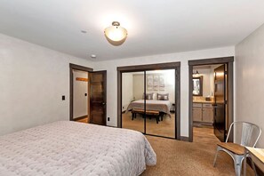 Un dormitorio con cama, escritorio y silla. Hay una puerta que da al baño y un armario.