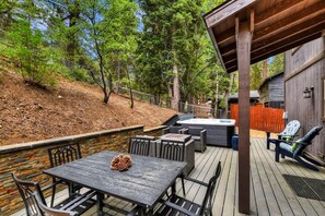 Un área de patio al aire libre con mesa y sillas, un jacuzzi y una terraza de madera.