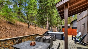 Una terraza al aire libre con un muro de piedra, una mesa con sillas y un jacuzzi.