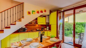 Una cocina moderna con armarios amarillos, una escalera de madera y un comedor con una mesa preparada para cuatro.