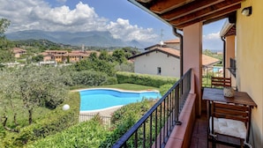 Un balcón con vistas a una piscina, una silla y una mesa.
