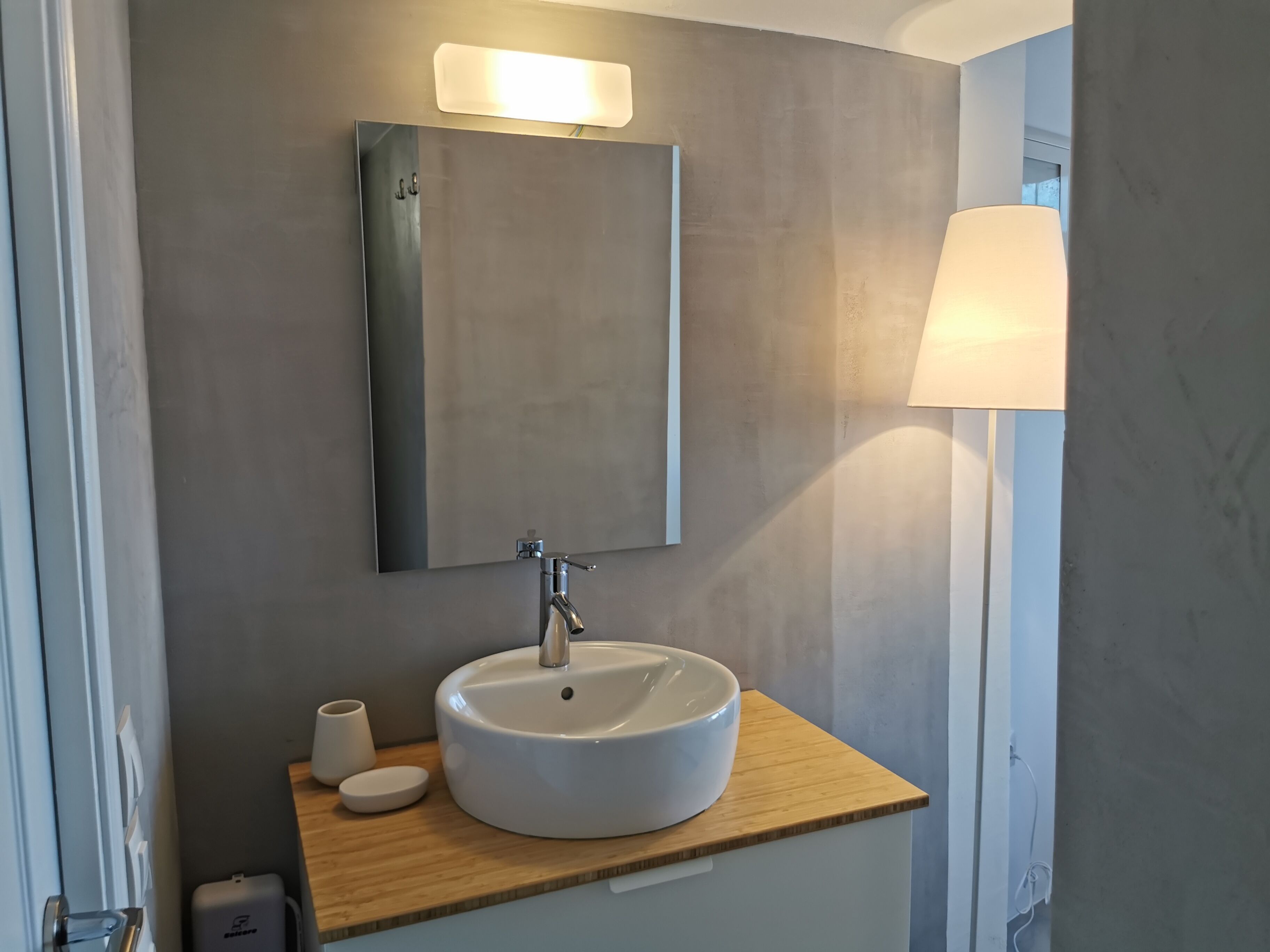 Een badkamer met een wit wastafel, een spiegel en een houten aanrecht.