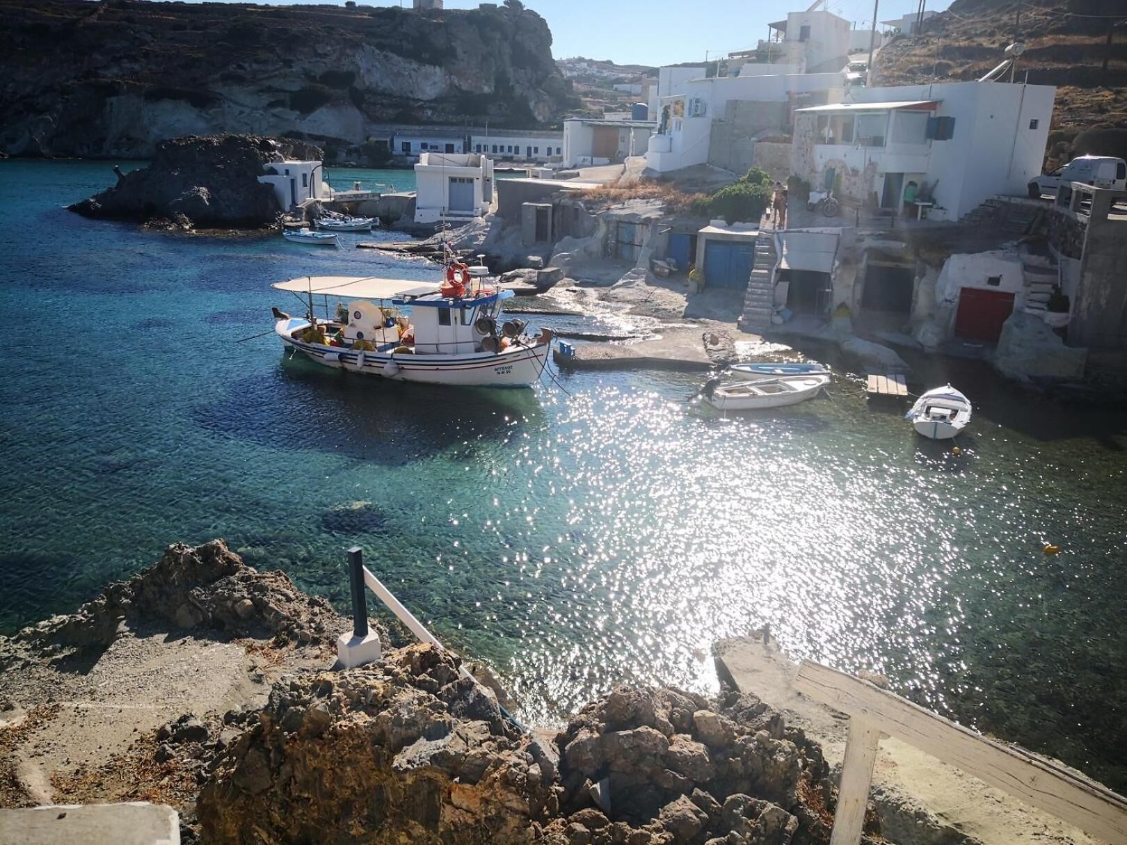 A coastal village with boats docked near rocky shores and white buildings.